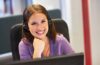 Customer service representative wearing a headset, smiling at the desk.